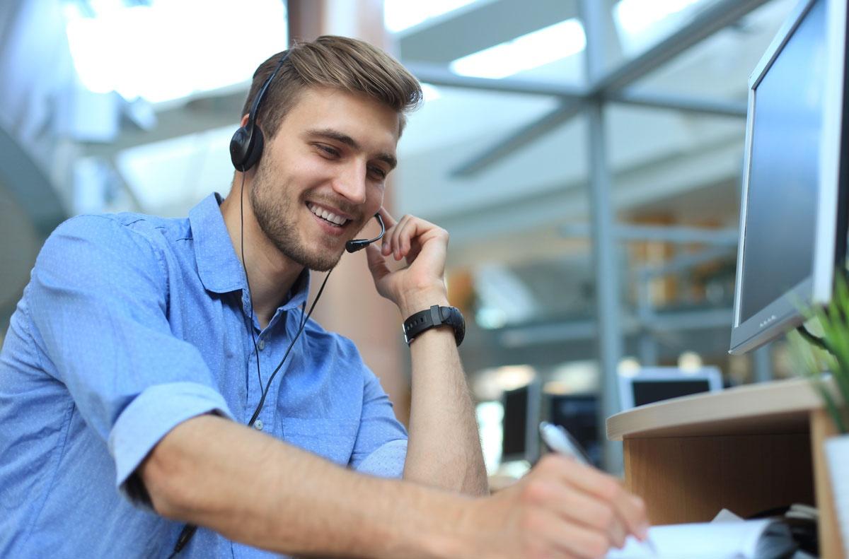 Man with a headset microphone taking notes in front of monitor